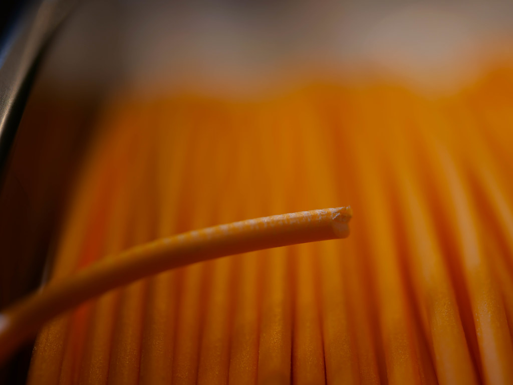 Gros plan sur un filament d'impression 3D et sa bobine, illustrant le choix entre deux composites carbone