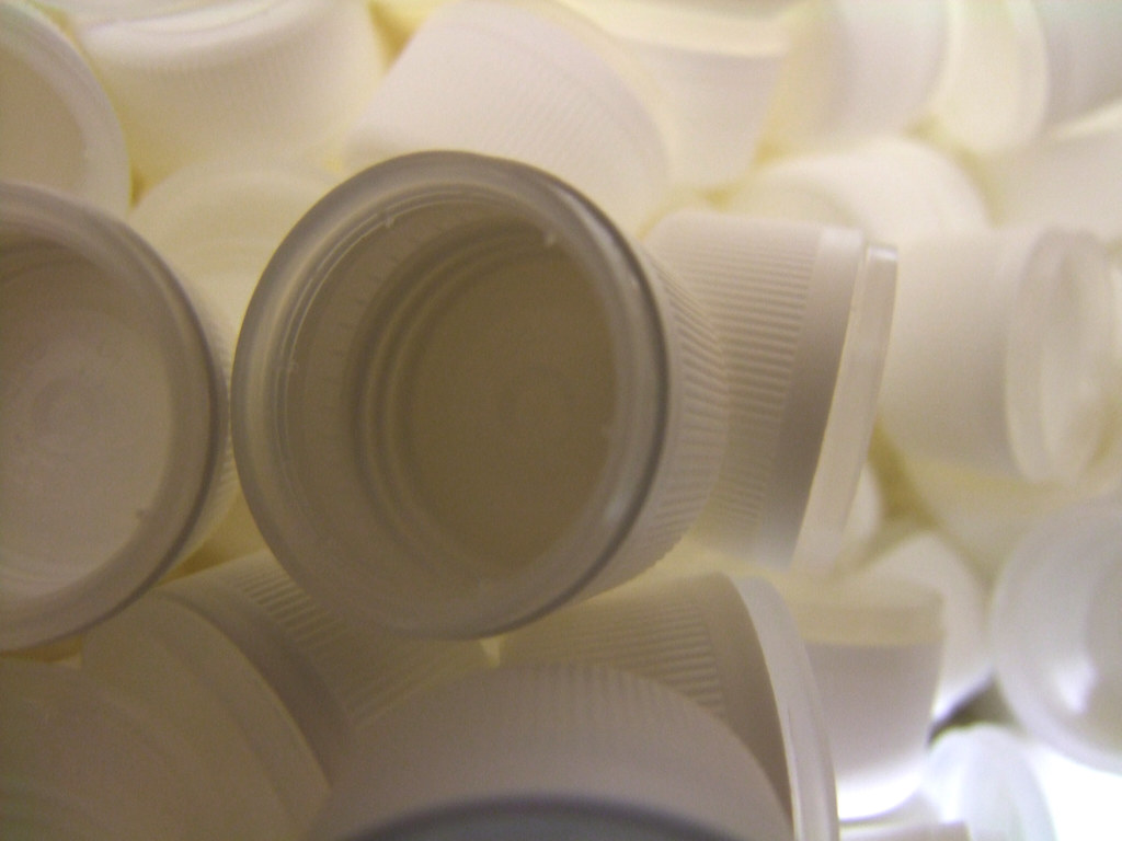 Assortiment de bouchons plastiques blancs sans marque, illustrant le prototypage d'emballage cosmétique
