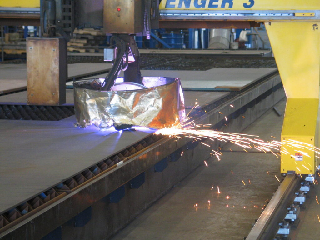 Tête de découpe CNC (plasma) sur portique, coupant une tôle plate en 2D, illustrant le principe de la découpe à plat face à l'impression 3D volumique