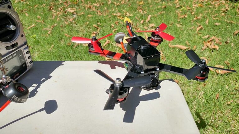 Drone de course FPV posé sur une table, avec support de caméra et hélices visibles, illustrant les accessoires imprimés en 3D