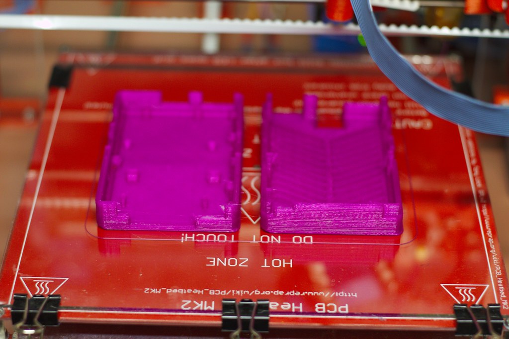 Deux boîtiers en plastique à parois fines venant d'être imprimés en 3D, illustrant le sujet de l'épaisseur de paroi minimale