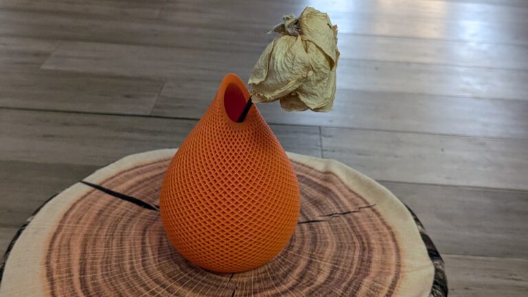 Vase orange imprimé en 3D dont l'ouverture laisse voir la cavité intérieure vide, illustrant une pièce évidée