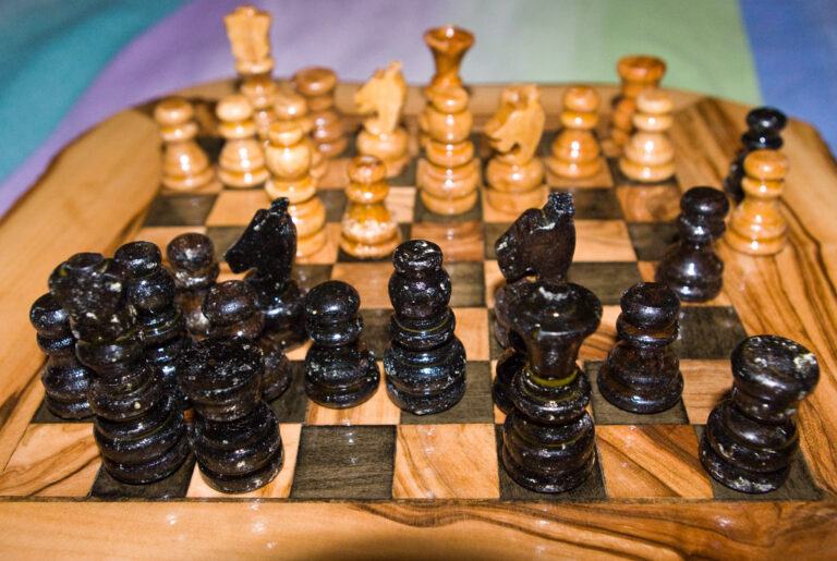 Plateau d'échecs en bois avec pions noirs et blancs complets, illustrant un jeu de société avec ses pièces