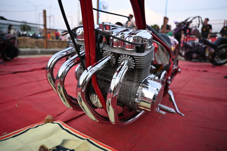 Détail d'un moteur de moto customisée avec échappements chromés polis, illustrant la personnalisation motocycliste