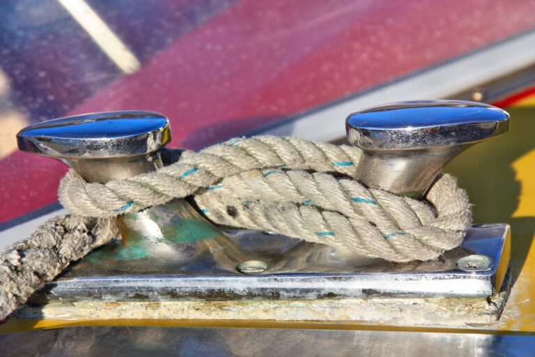 Taquet chromé de bateau avec un cordage d'amarrage noué, illustrant l'accastillage de pont exposé aux intempéries