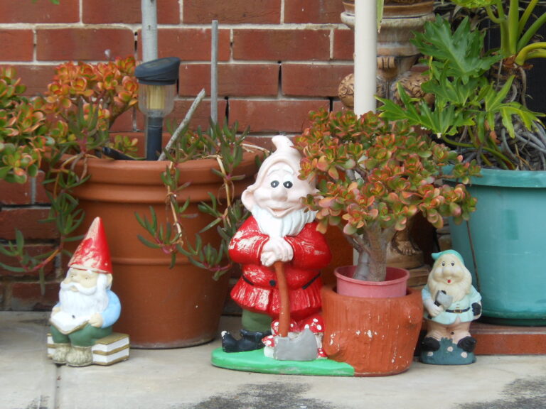 Figurines décoratives de jardin exposées au soleil parmi des plantes en pot