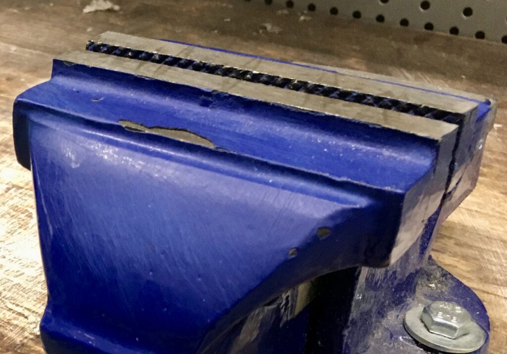 Étau d'établi en métal, illustrant un usage typique d'outillage rigide et résistant en atelier