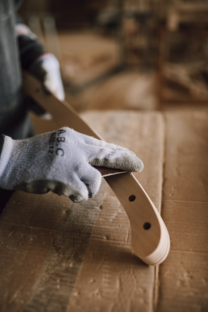 Artisan ponçant une pièce à la main, illustrant l'étape de ponçage des finitions poncée et premium