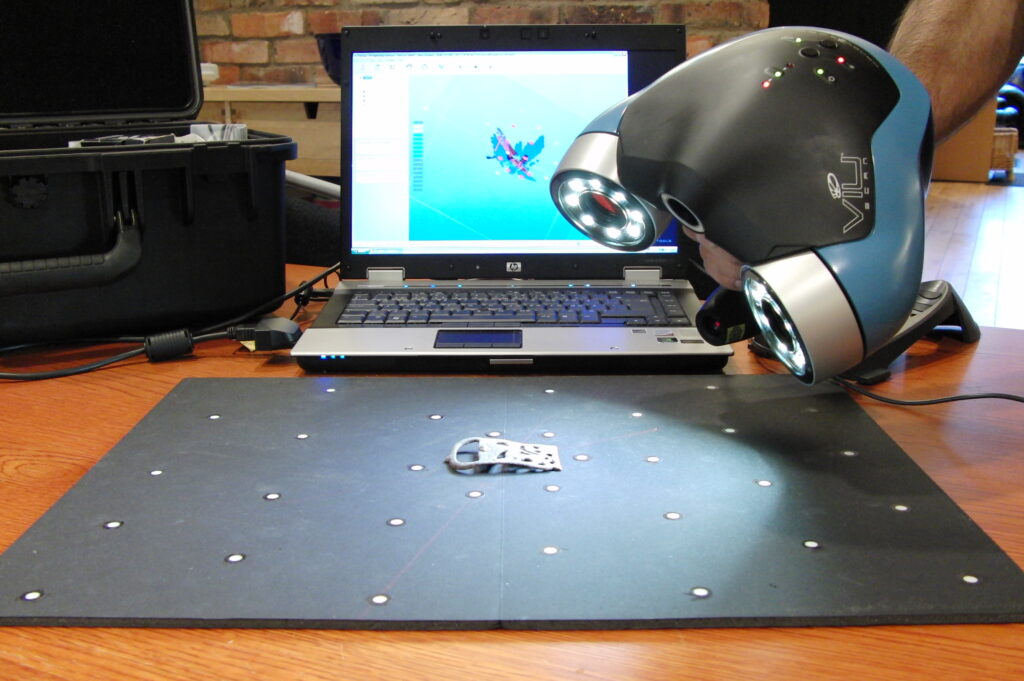 Scanner 3D portable en train de numériser une petite pièce métallique posée sur un plateau de calibration