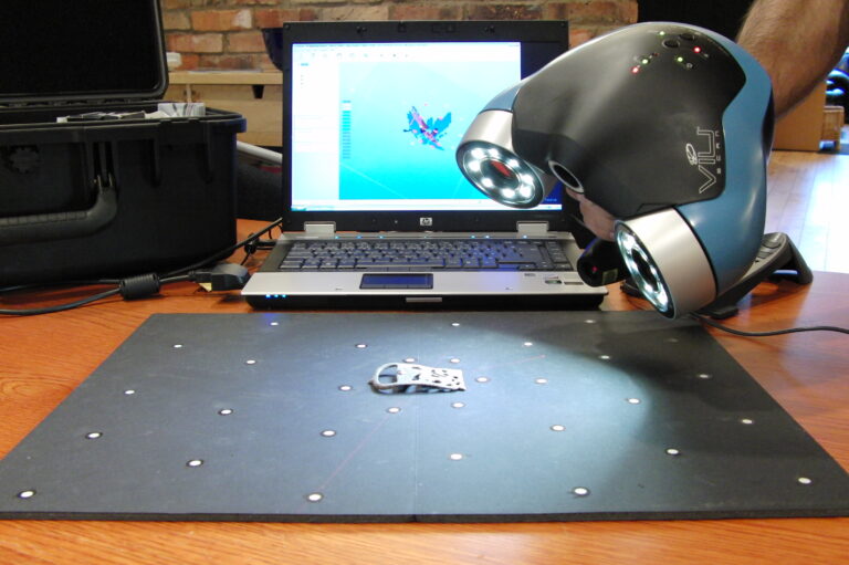 Scanner 3D portable en train de numériser une petite pièce métallique posée sur un plateau de calibration