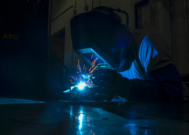Ouvrier soudant une pièce métallique, illustrant le travail de la tôle et du métal en atelier